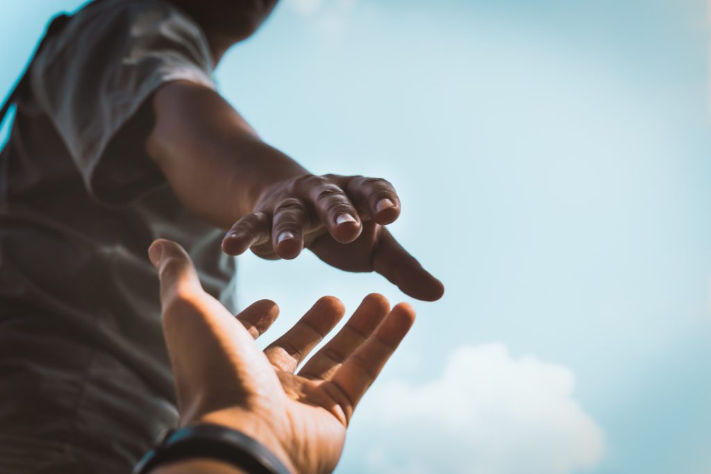 Cropped hands reaching out to help each other