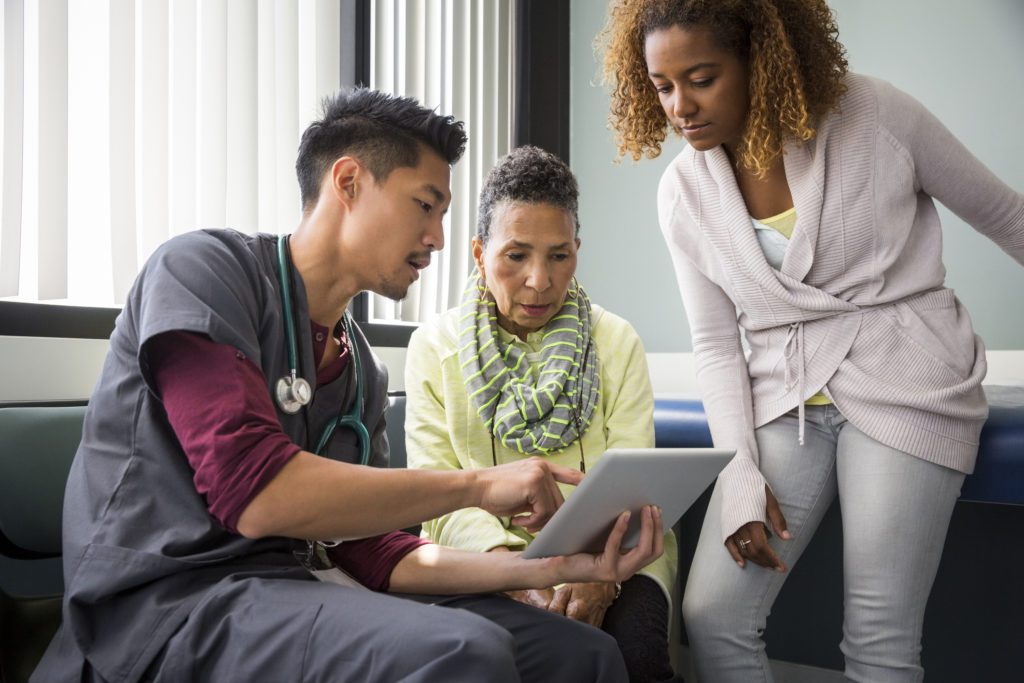 Male nurse consulting with senior female patient and adult daughter